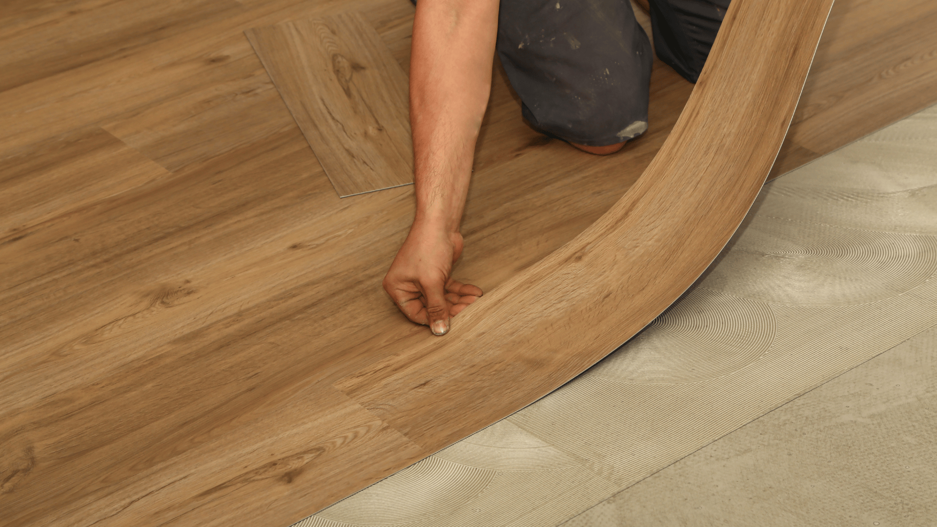 Installer flexing a light wood-look vinyl plank to click it into the surrounding floor