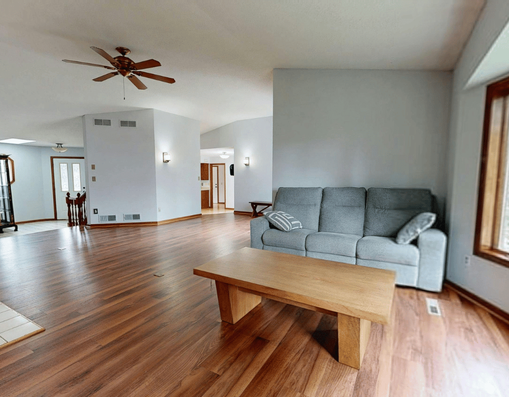Living room with warm golden refinished hardwood flooring, a grey sofa and a wooden coffee table