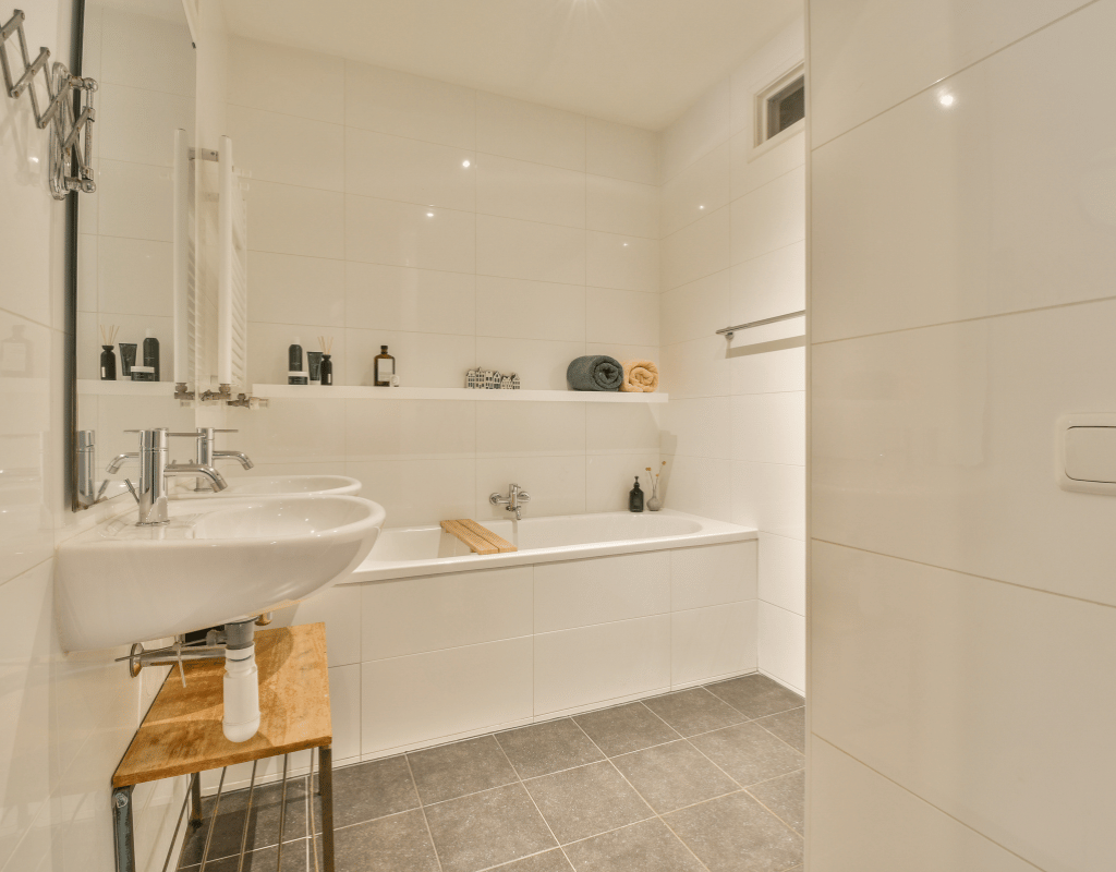 Bright bathroom with large-format tile flooring, a tiled shower surround, white sink and built-in bathtub