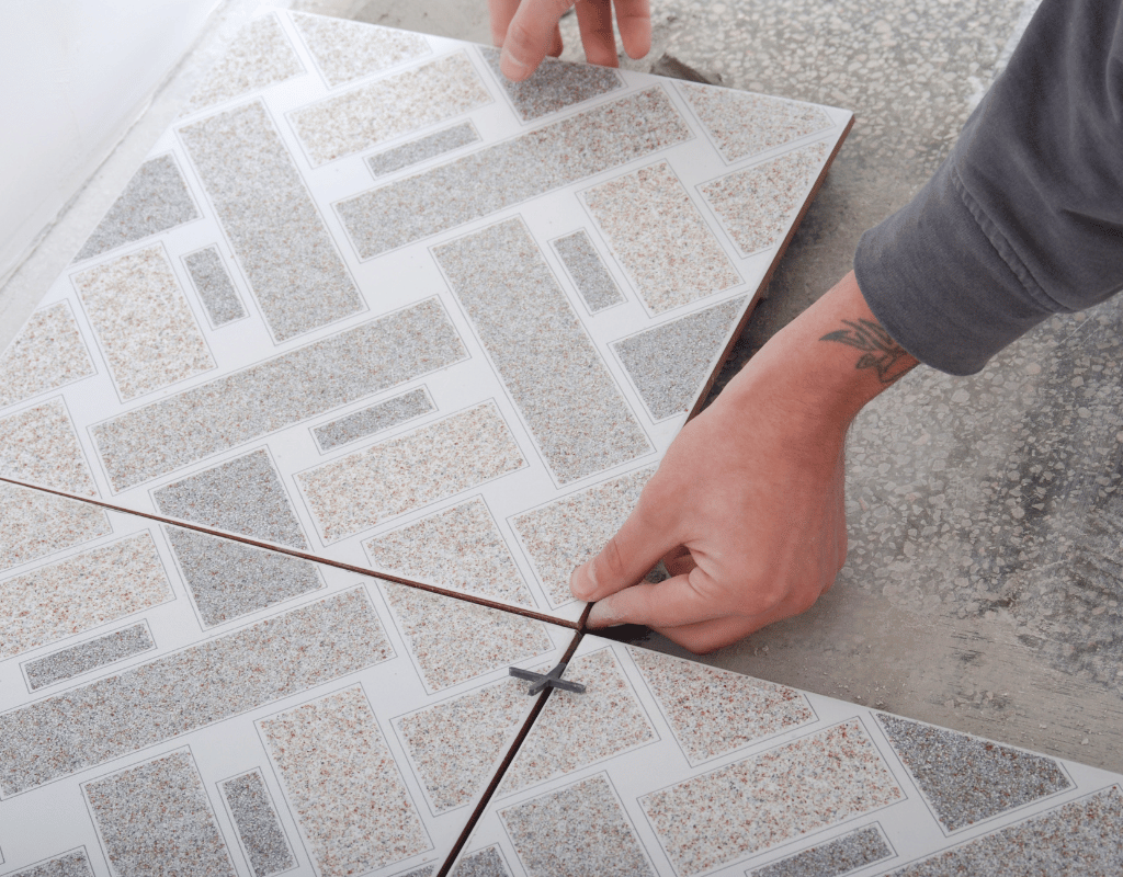 A person using a manual tile cutter to score a speckled granite-look floor tile
